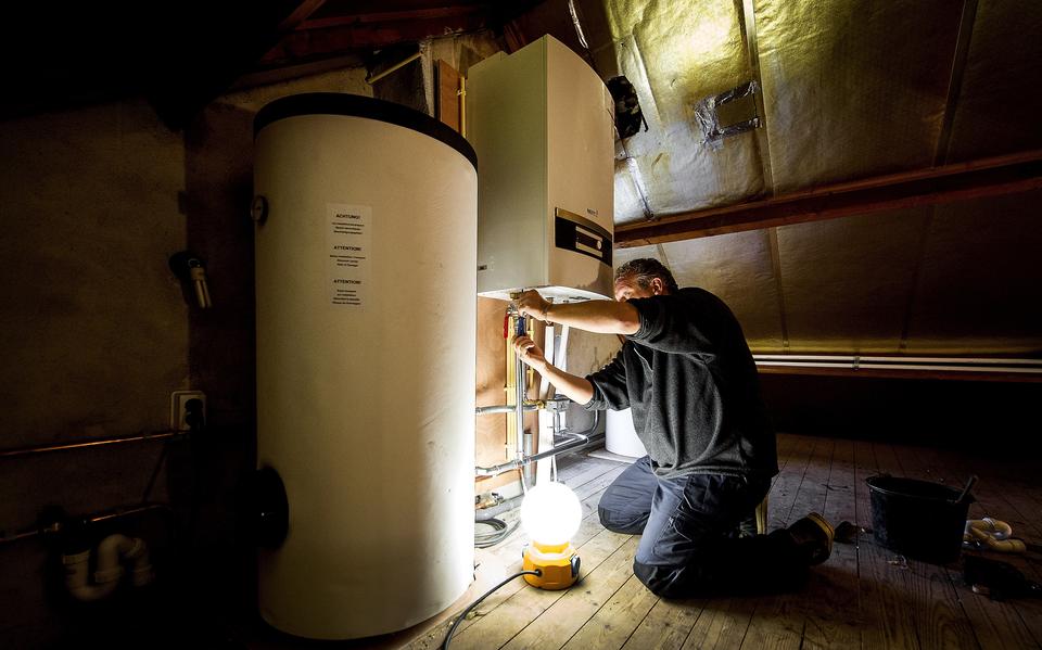 Een installateur installeert een warmtepomp.
