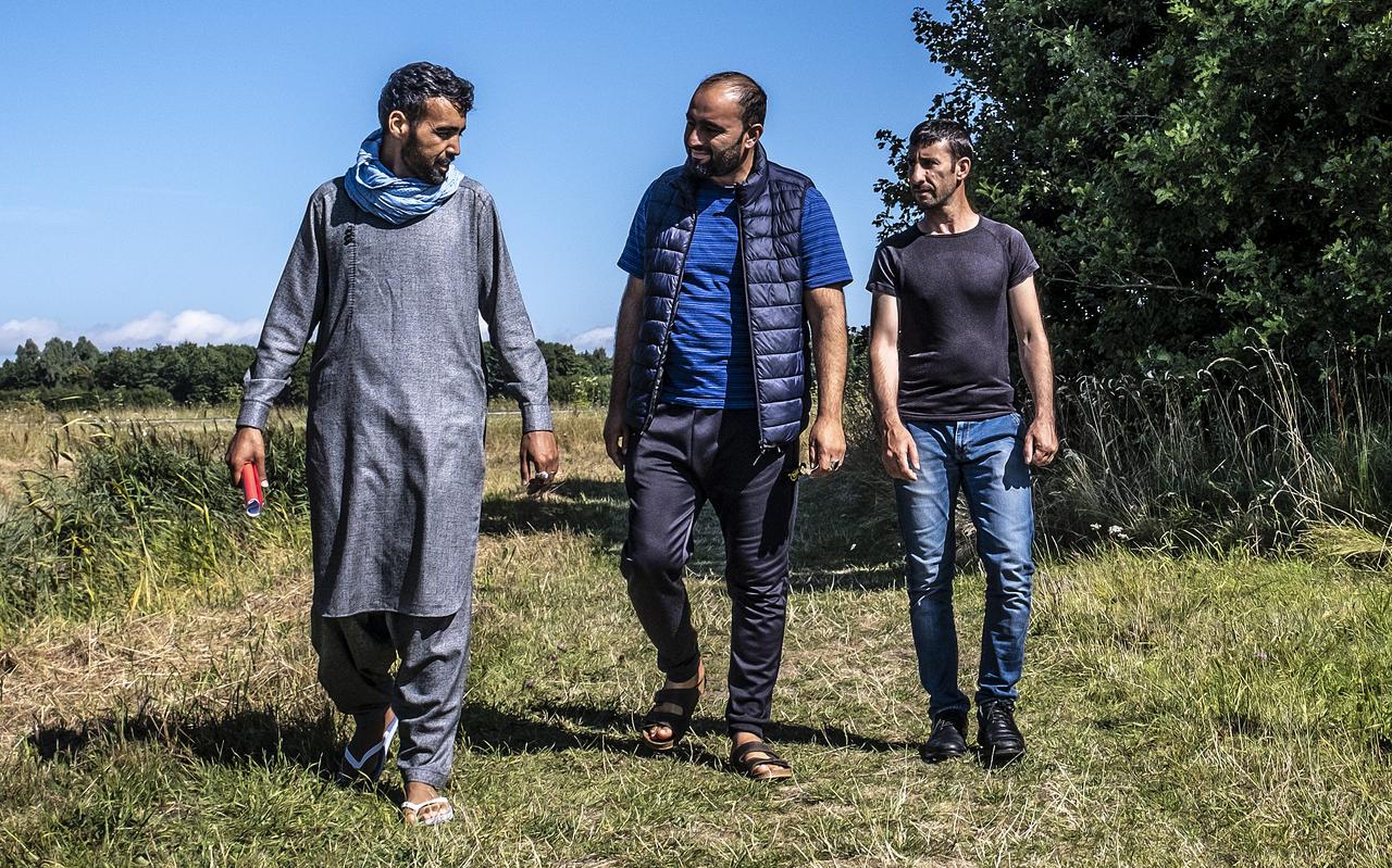 Massoud Satari uit Kunduz wandelt samen met Waheedullah Qamari uit Mazar Sharif en Gamshed Shahzad uit Maidan Wardak buiten de poort van de kazerne in de Lauwersmeerpolder.