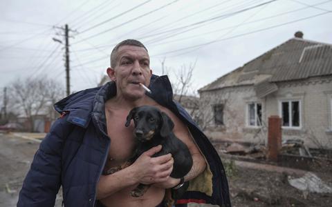Een man in Marioepol beschermt zijn hond op de dag van de Russische invasie. 