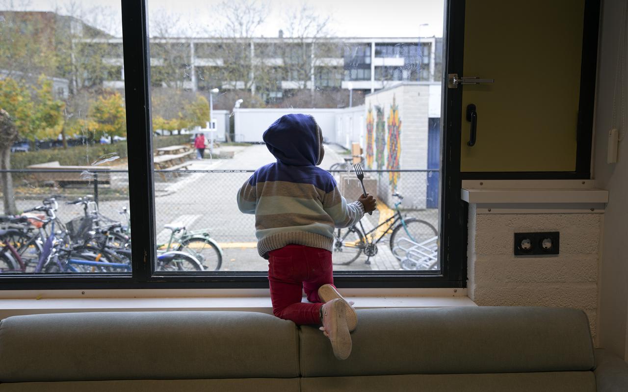 Kind kijkt uit het raam van een noodopvanglocatie in Oss.