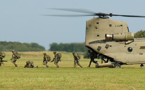 Militairen van de Luchtmobiele Brigade rennen uit de Chinook-helikopter die net is geland.  