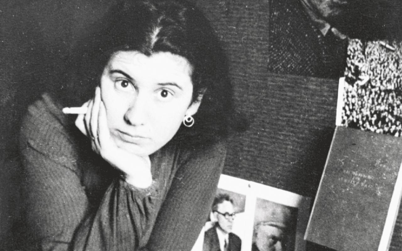 Etty Hillesum op haar kamer met aan de wand portretten van onder anderen de Russische schrijver Ilja Ehrenburg en de jonge Stalin (met geruite sjaal), 1937.