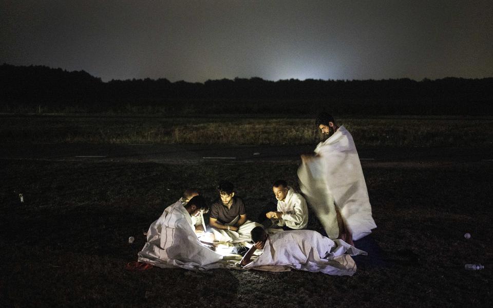 Niet iedereen slaapt in de drukte onder de luifels, sommige groepjes zonderen zich af. Beeld uit reportage 'Een nacht in het tentenkamp van Ter Apel'.