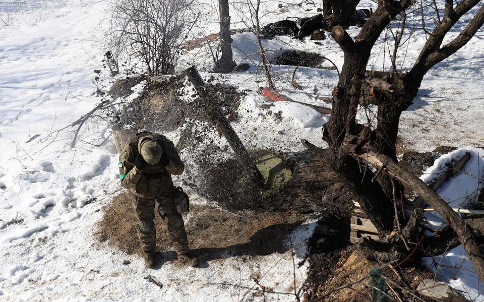 Een Oekraïense soldaat bedekt zijn oren terwijl hij een mortier afvuurt.