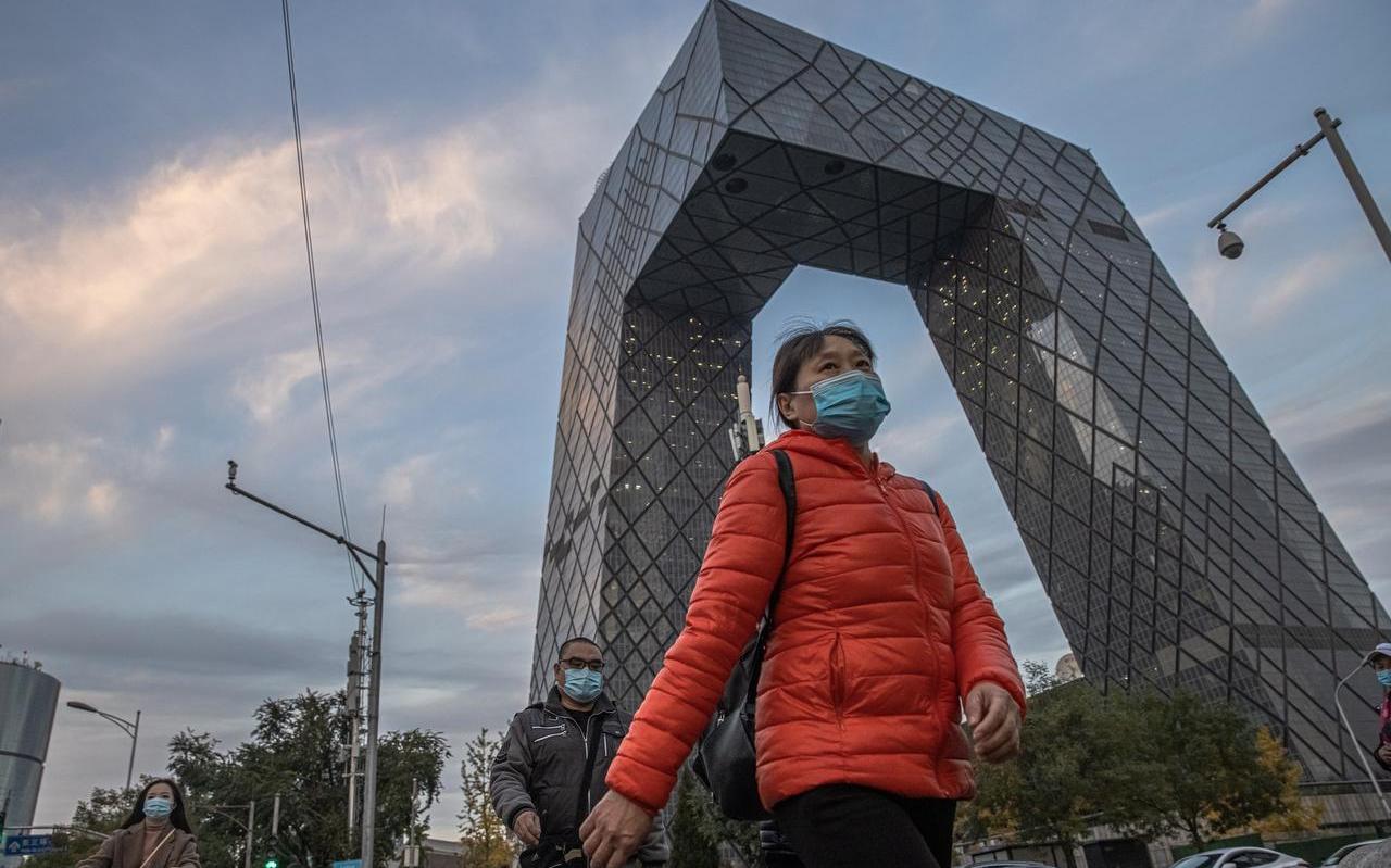 Een vrouw in Beijing draagt een mondkapje in het zakencentrum van de stad. Een vrouw in Beijing draagt een mondkapje in het zakencentrum van de stad.