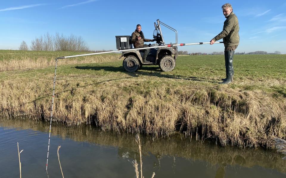 Twee medewerkers van Wetterskip Fryslân peilen de waterdiepte in een hoofdwatergang.
