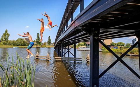 De brug in de wijk Oudvaart in Sneek is in de zomer een geliefde plek voor jongeren. Massaal springen ze er van af voor een verfrissende plons in het water. FOTO NIELS DE VRIES