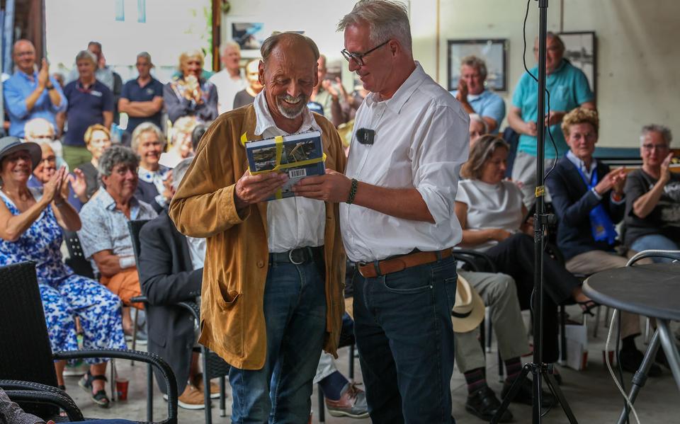 Schrijver Klaas Smit (r) overhandigt botenbouwer Pier Piersma uit Heeg het eerste exemplaar van het boek over Piersma en zijn scheepswerf.