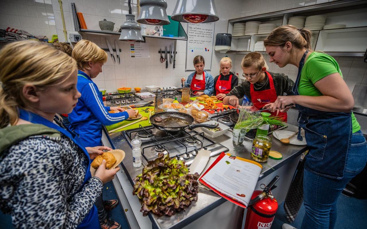 In de keuken van wijkcentrum De As in Heerenveen bereiden kinderen hun eigen maaltijd: wortelsalade en een broodje zelfgemaakte hamburger. In de keuken van wijkcentrum De As in Heerenveen bereiden kinderen hun eigen maaltijd: wortelsalade en een broodje zelfgemaakte hamburger.