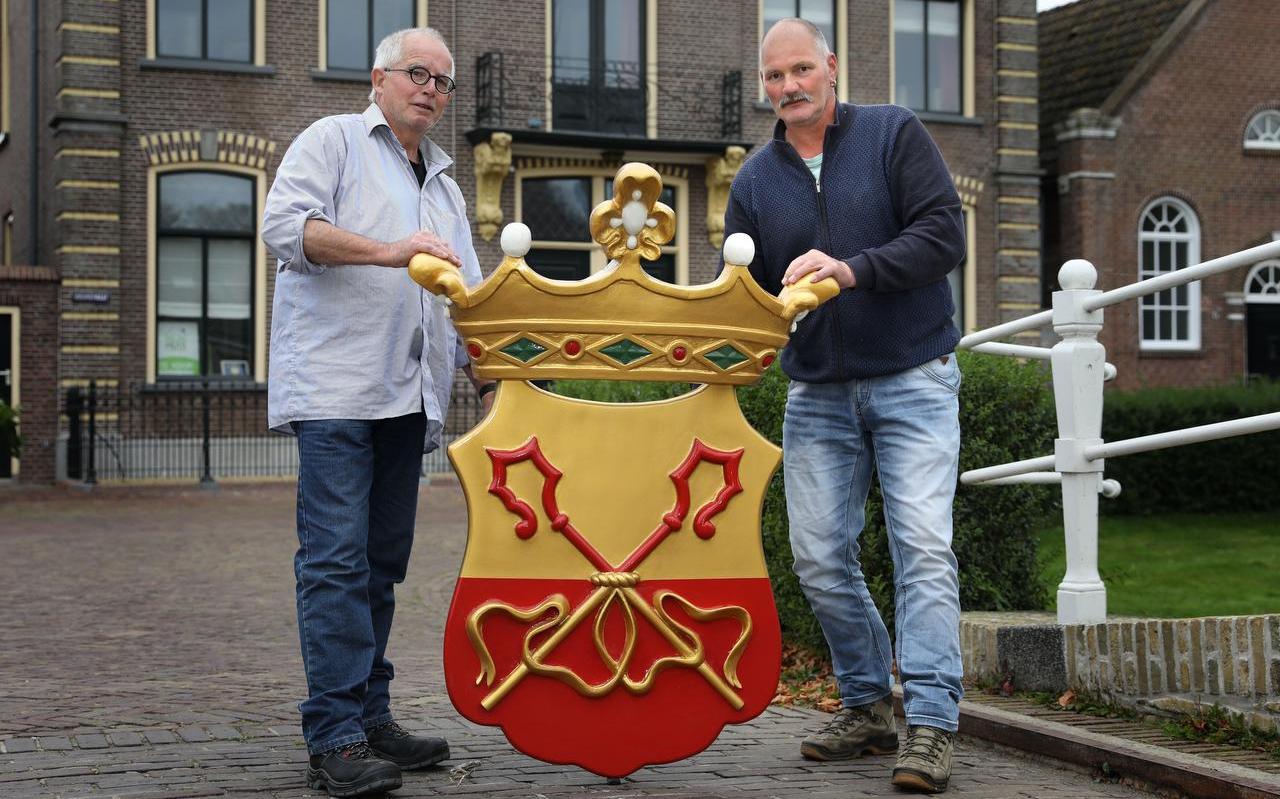 Klaas Zwaan en Alex Westra aan weerszijden van het nieuwe wapen van Stavoren, op de achtergrond het voormalige stadhuis waar het weer komt te hangen. Klaas Zwaan en Alex Westra aan weerszijden van het nieuwe wapen van Stavoren, op de achtergrond het voormalige stadhuis waar het weer komt te hangen.