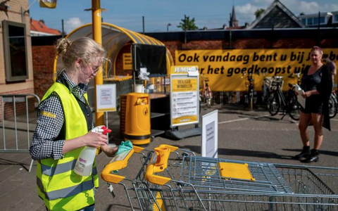Een medewerkster van de Jumbo in de Eksterstraat desinfecteert de handvatten van de winkelwagentjes. Dat gebeurt niet meer bij alle supermarkten. FOTO Hoge Noorden/Jacob van Essen