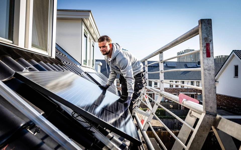 Een monteur legt zonnepanelen op een dak.