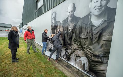 Wendy Gooren en Gerlof Jensma kijken toe hoe een metershoog portret van Gerlof, broer Sjoerd en de drie zonen van broer Goffe op een van de schuren wordt aangebracht.