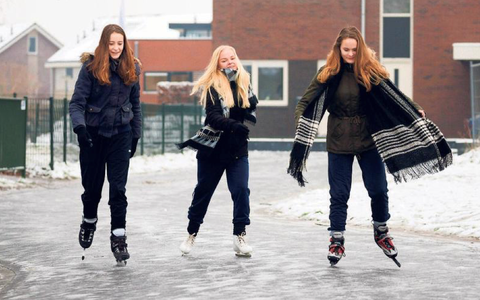Iris Baron, Daphne Pit en Sanne Baron (van links naar rechts) schaatsen op straat in Oosterwolde.