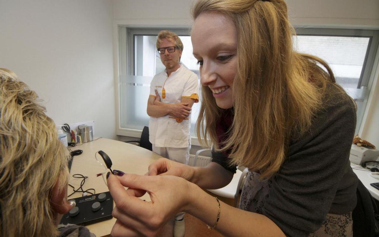 Kyra Geys brengt de oortjes aan waarmee een tinnitus-patient wordt blootgesteld aan tonen die het oorsuizen moeten terugdringen. Op de achtergrond kijkt kno-arts Xander de Vries van Tjongerschans toe. FOTO SIMON BLEEKER