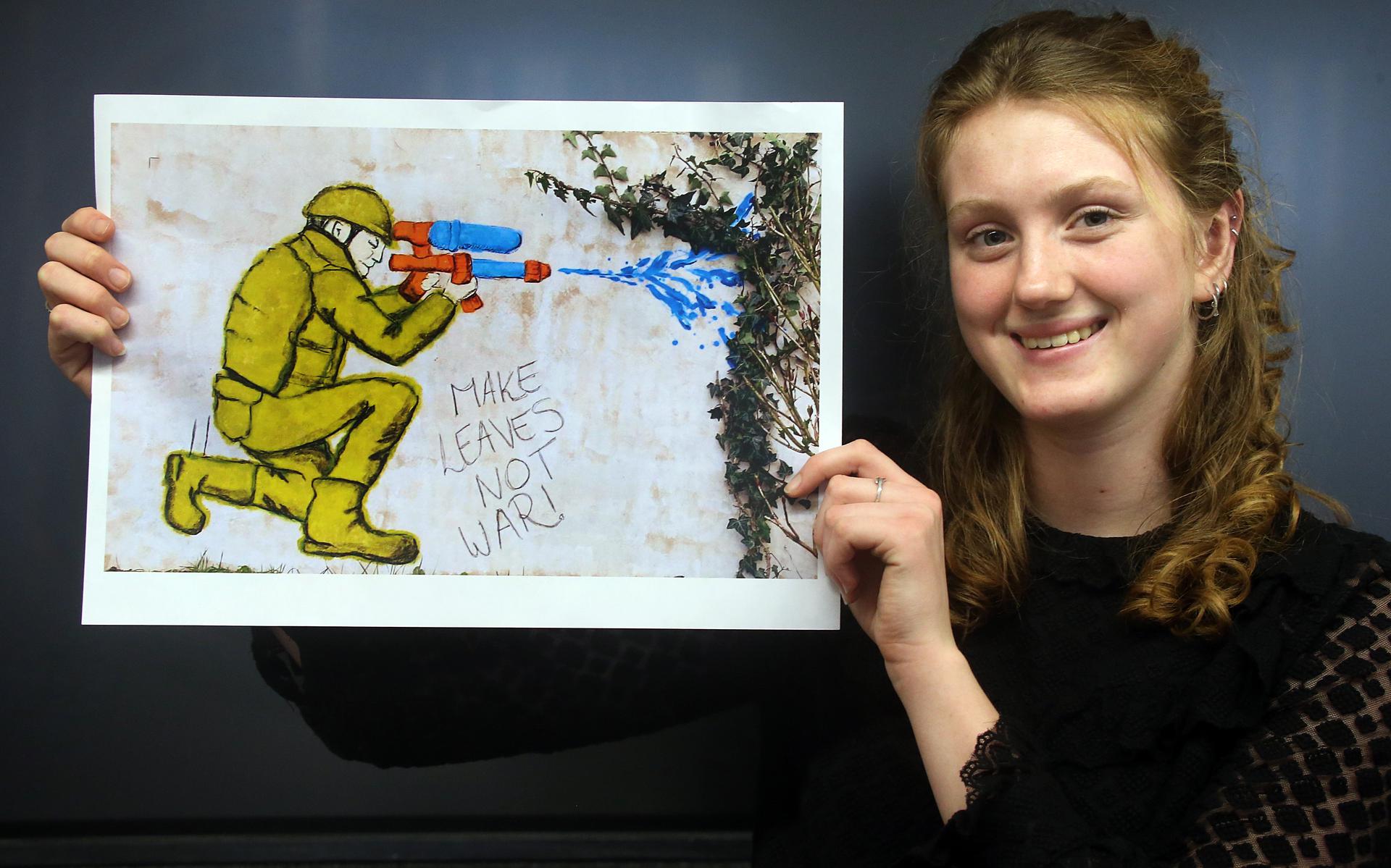 Emma Kienstra met een foto van haar kunstwerk, geïnspireerd op de werken van street art kunstenaar Banksy. 