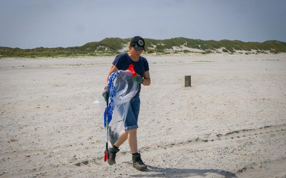 Een vrijwilliger helpt in de zomer van 2022 gewapend met een grijper het strand van Ameland schoon te maken. 