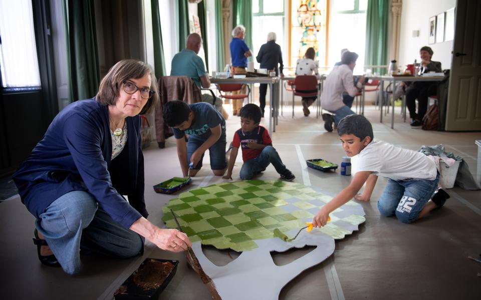 Germa Kamsma-Kunst knutselt samen met Jenushan (links) Merushan (midden) en Robishan aan een boom die nu onderdeel is van een tentoonstelling over BOSK in de Bonifatiuskerk. 