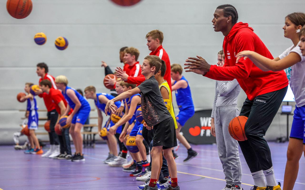 Basketballer Shaquille Doorson (2.13 meter) van Aris geniet tijdens het geven van een clinic met Friese jeugdspelers.
