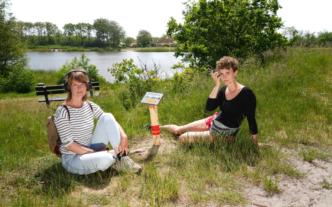 Anouk van Kolfschoten (links) en Lola Bogaert bij een van de bordjes met QR-codes die de verhalen van hun community-kunstproject Het Eiland Vertelt ontsluiten.