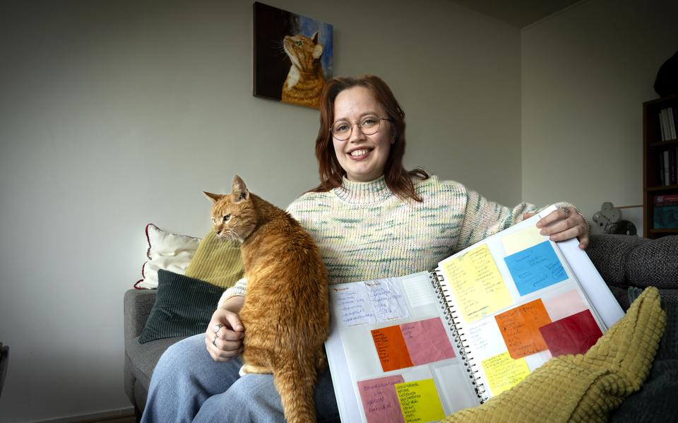 Anieke Barth en de 17-jarige kater Woekie op de bank met de map met verzamelde boodschappenlijstjes.