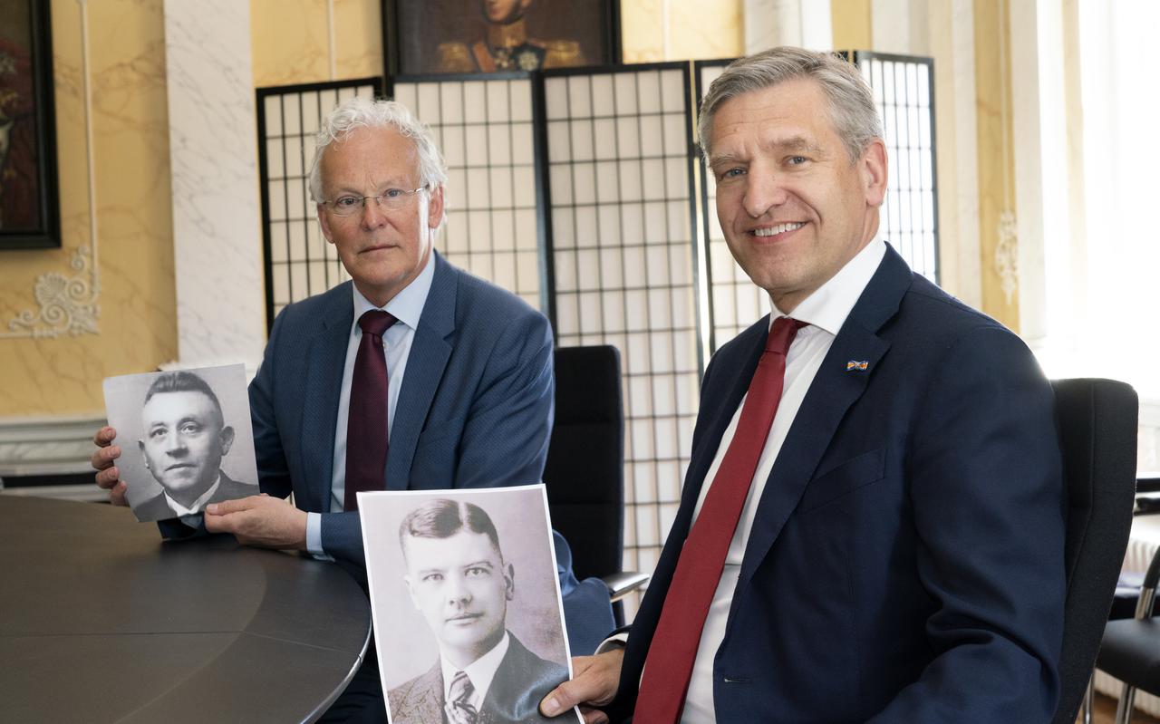 Burgemeester Sybrand Buma van Leeuwarden en burgemeester Jan Rijpstra van Smallingerland met in hun hand een foto van hun grootvaders die beiden tijdens de Tweede Wereldoorlog omkwamen in kamp Neuengamme.