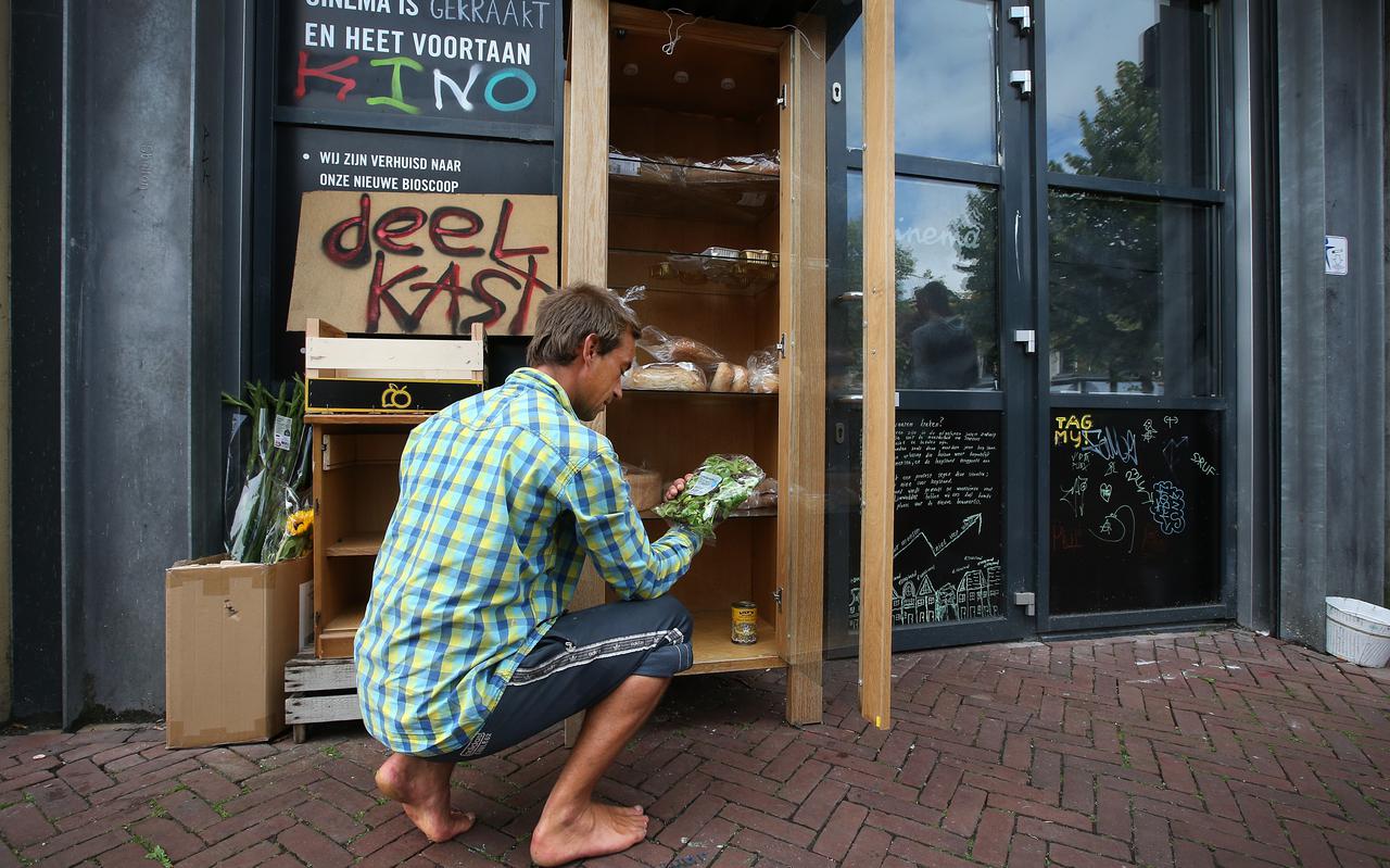 Jorik (29) stopt eten in de deelkast voor het kraakpand aan de Nieuwestad in Leeuwarden.