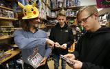 Annetol Griskov, eigenaar van Spellekijn, laat pakjes Pokémon-kaarten zien aan Demian van der Wagen en Max Grijpstra die er een paar uitzoeken.