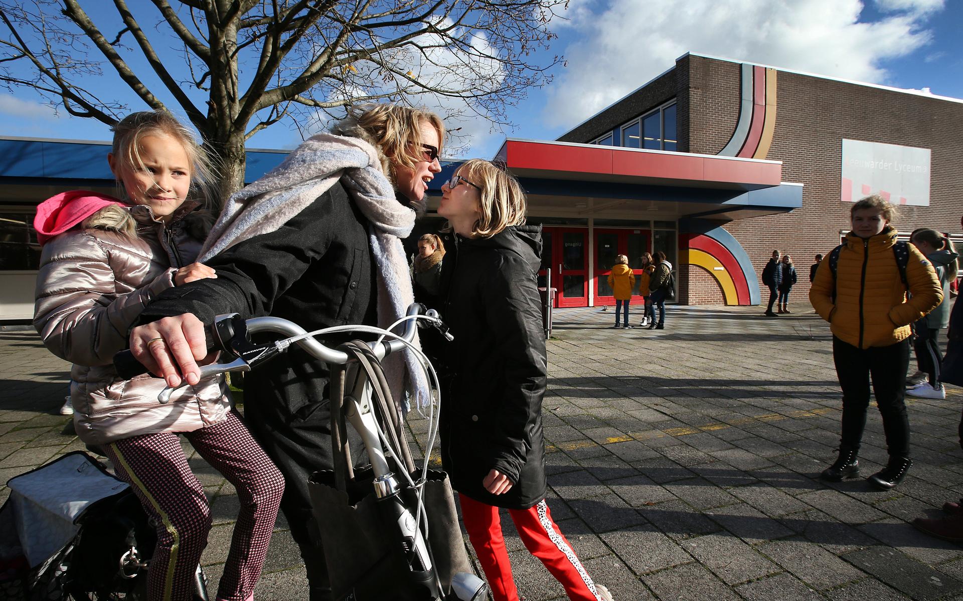 Martha Warrink, met dochter Eva (8) achterop de fiets, neemt afscheid van Anouk (12), die een kijkje gaat nemen op het Leeuwarder Lyceum.