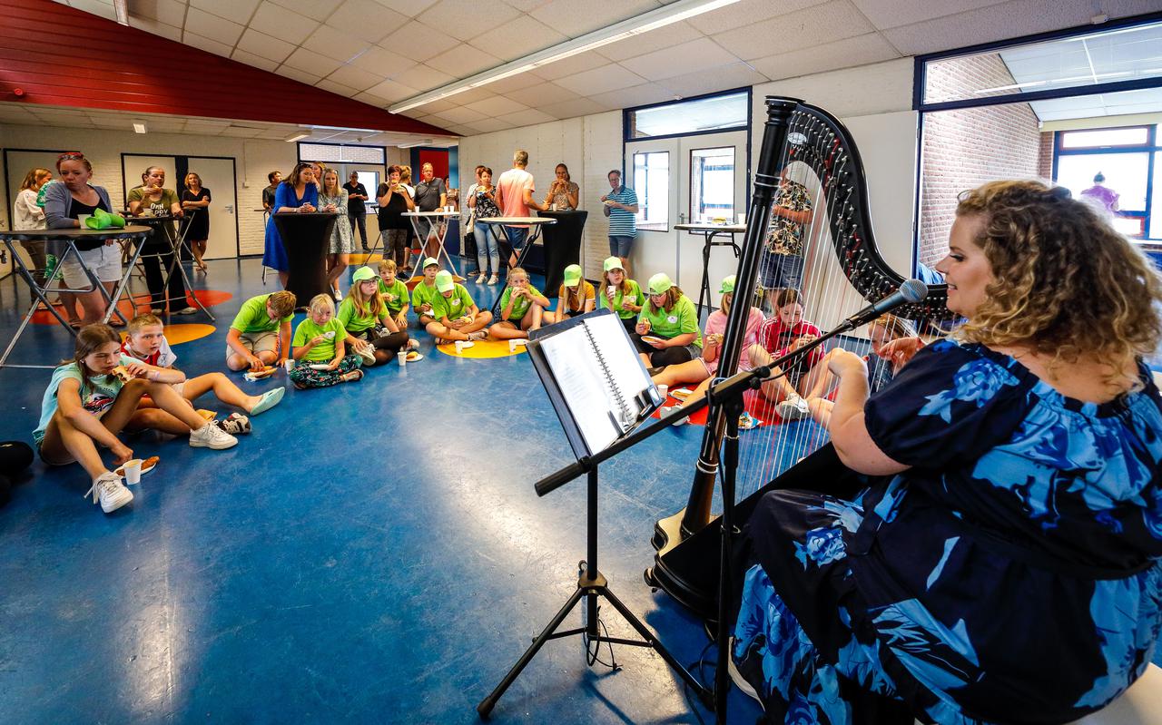 De zestien leerlingen luisteren naar zangeres en harpiste Iris Kroes.