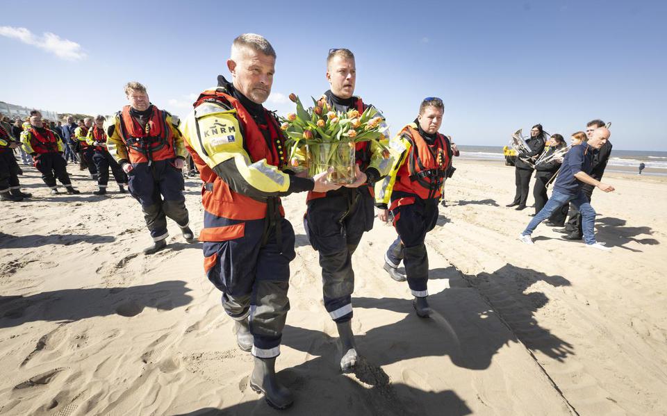 Vrijwilligers van de KNRM brengen de tulpen richting de zee.
