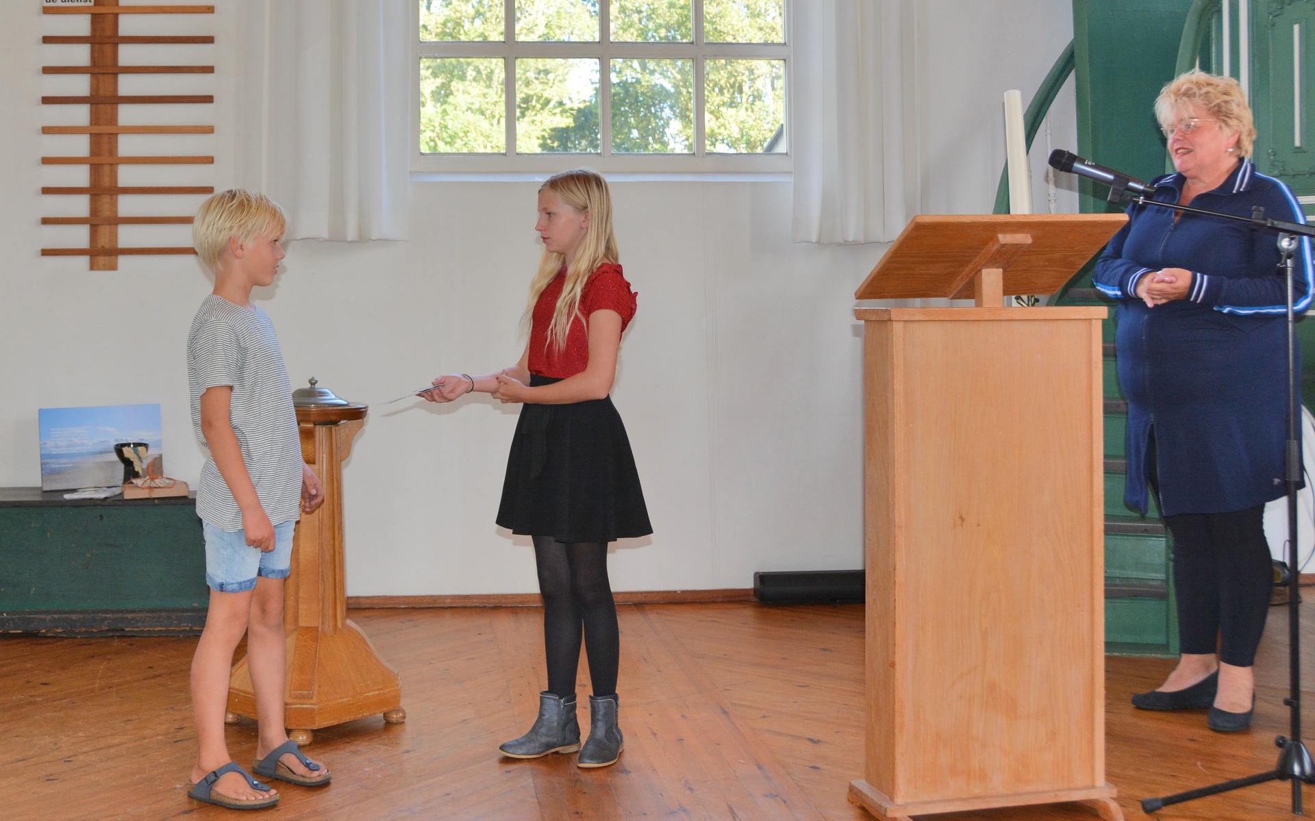 Noah Dam (links) krijgt de ZKV jongerenprijs van kinderburgemeester Sabine AB. Burgemeester Ineke van Gent, voorzitter van de jury, kijkt toe. Foto Romy Dam