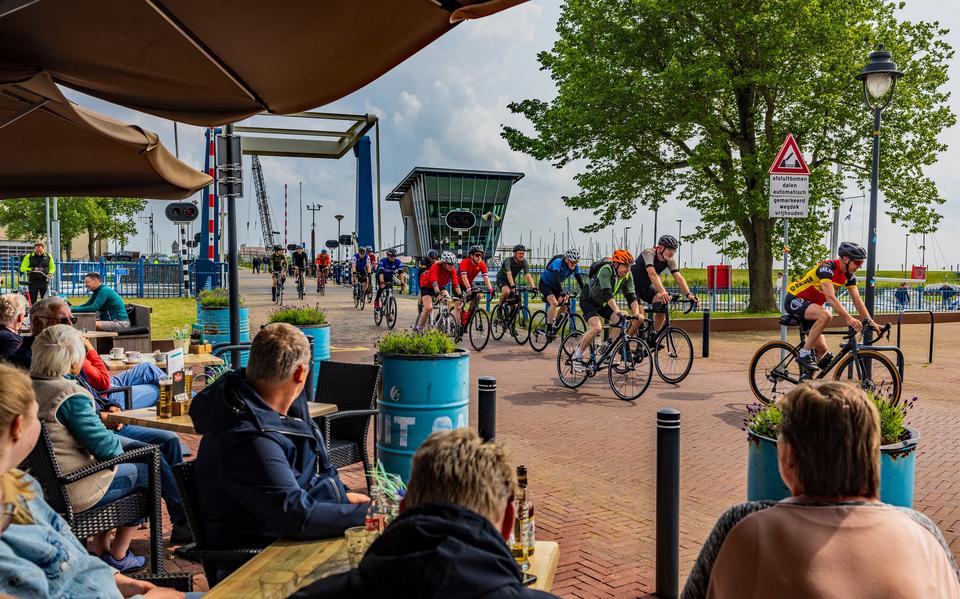 Dagjesmensen kijken uit op de Elfstedenfietsers op de Stadsfenne in Stavoren.