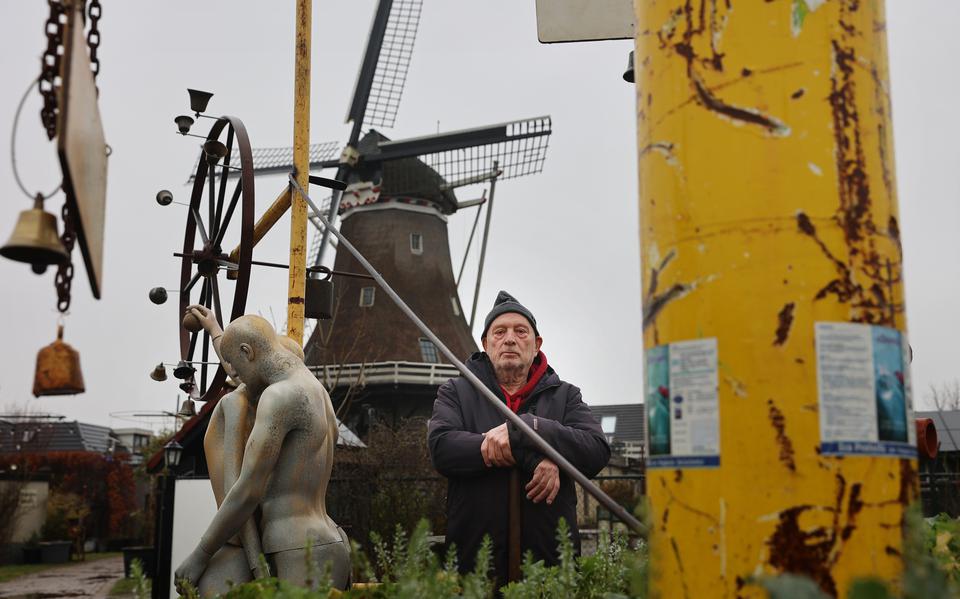 Sibe Palma tussen enkele kunstobjecten met op de achtergrond zijn molen, De Korenaar. 