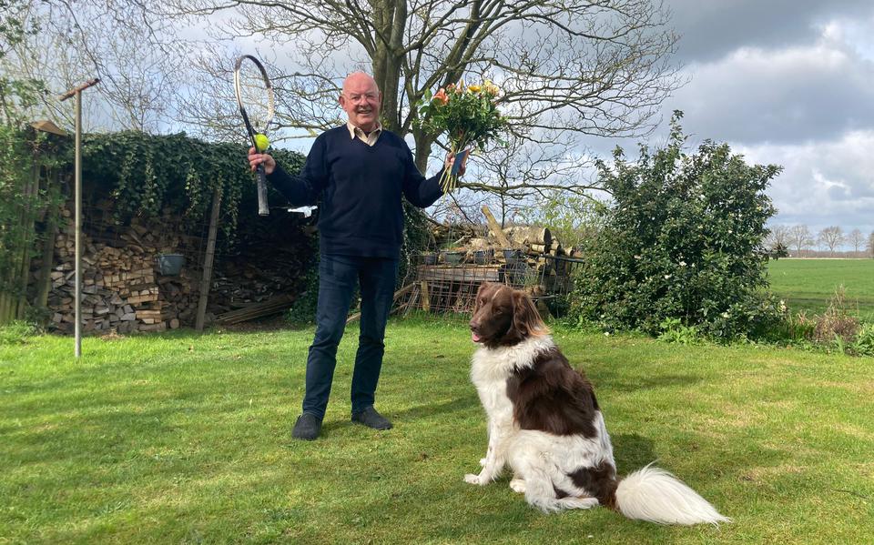 Anne Lieuwes met zijn hond Does. Lieuwes heeft in zijn linkerhand de bloemen en de waardebon die hij kreeg bij zijn afscheid van de tennisclub.