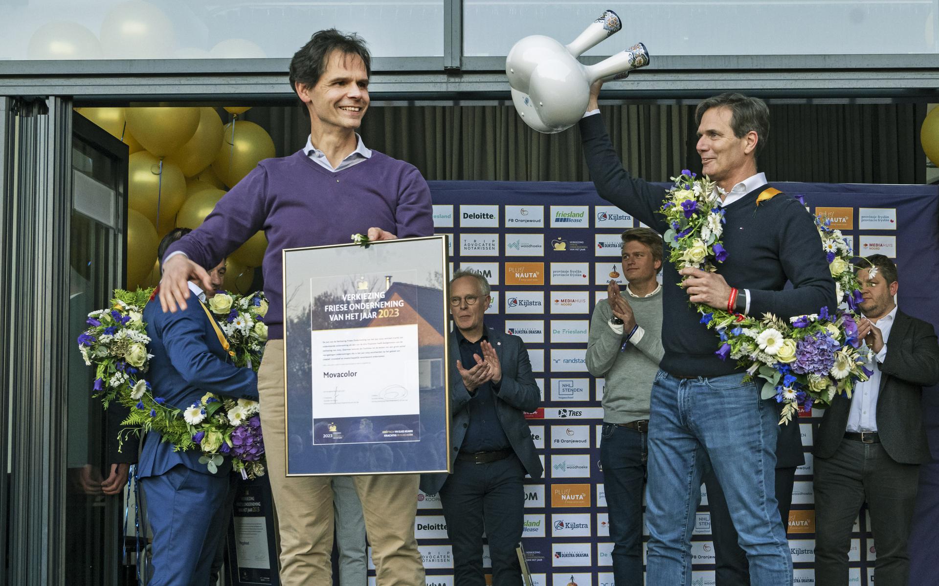 Marc Aandeweg en Bas Nieuwenhuis van Movacolor krijgen de bokaal voor de Friese onderneming van het jaar uit handen van commissaris van de Koning Arno Brok.