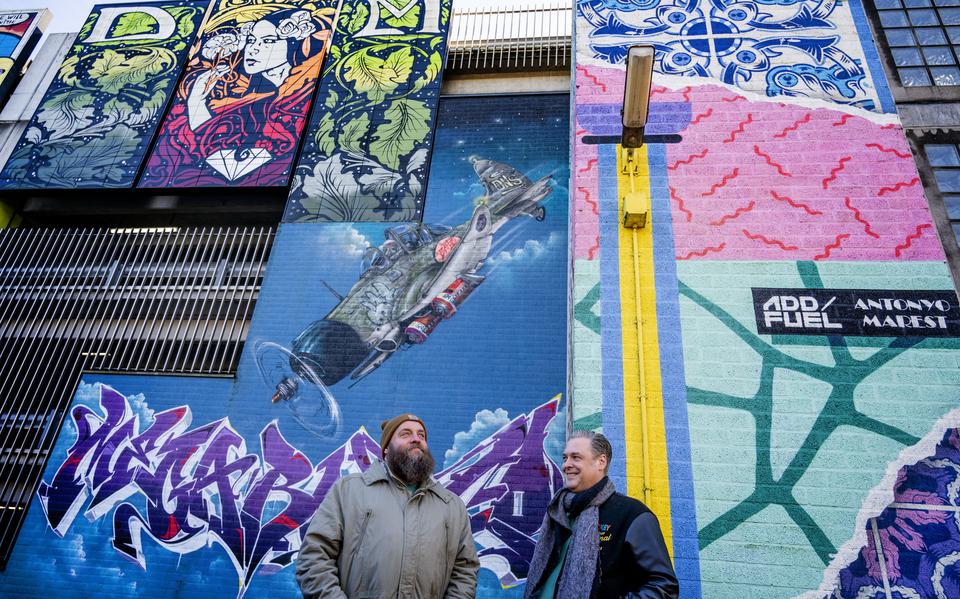 Peter Reen (links) en Serge Hollander staan voor parkeergarage De Klanderij in Leeuwarden met op de achtergrond een van de muurschilderingen.