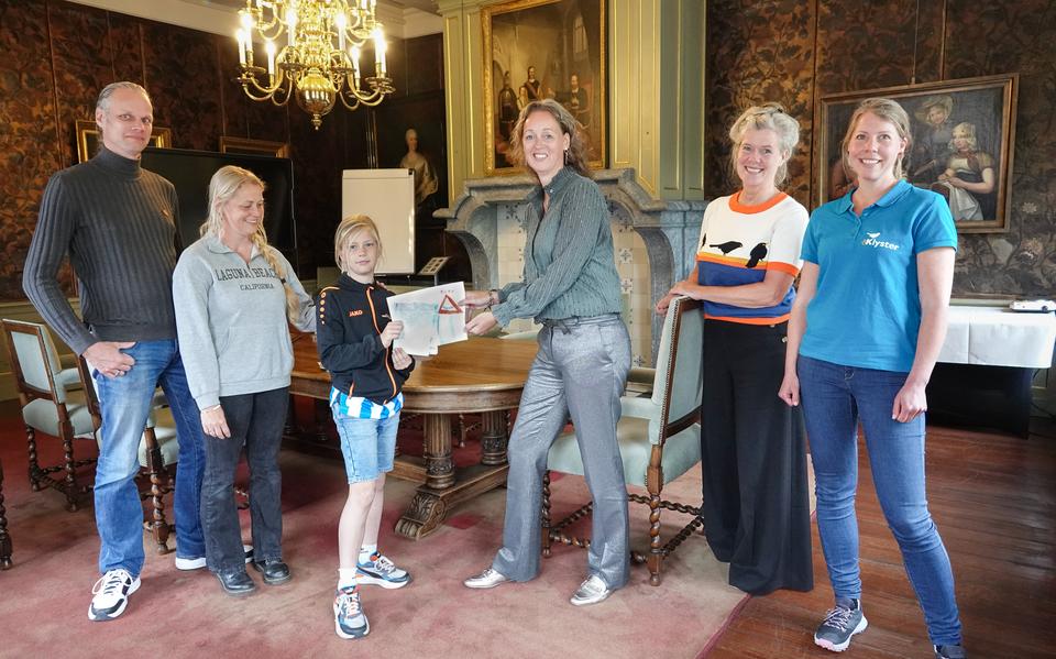 Xaveer Kobus overhandigt de tekening van het nieuwe bord aan wethouder Hanneke Jouta. Links zijn vader en moeder, rechts Marjolein Staal en Mirja Brandorff van De Klyster. 