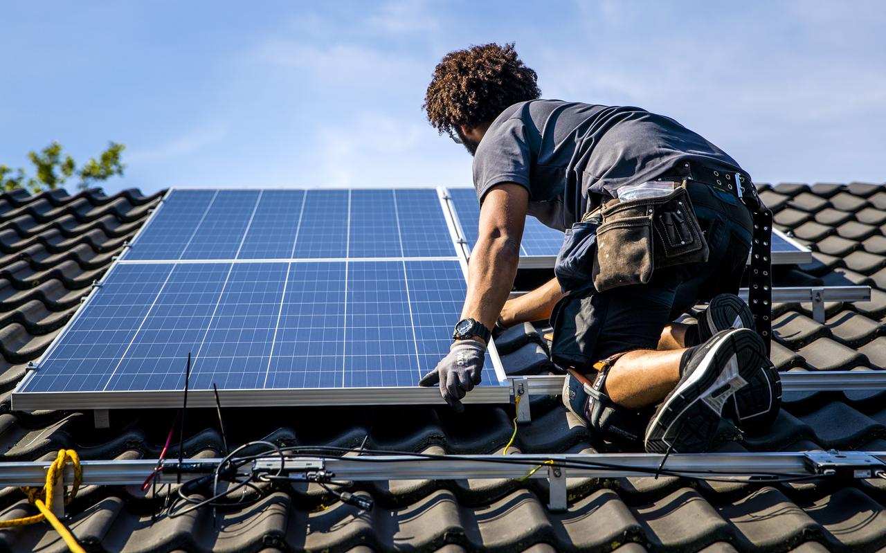 Een installateur plaatst zonnepanelen op het dak van een woonhuis. Een installateur plaatst zonnepanelen op het dak van een woonhuis.