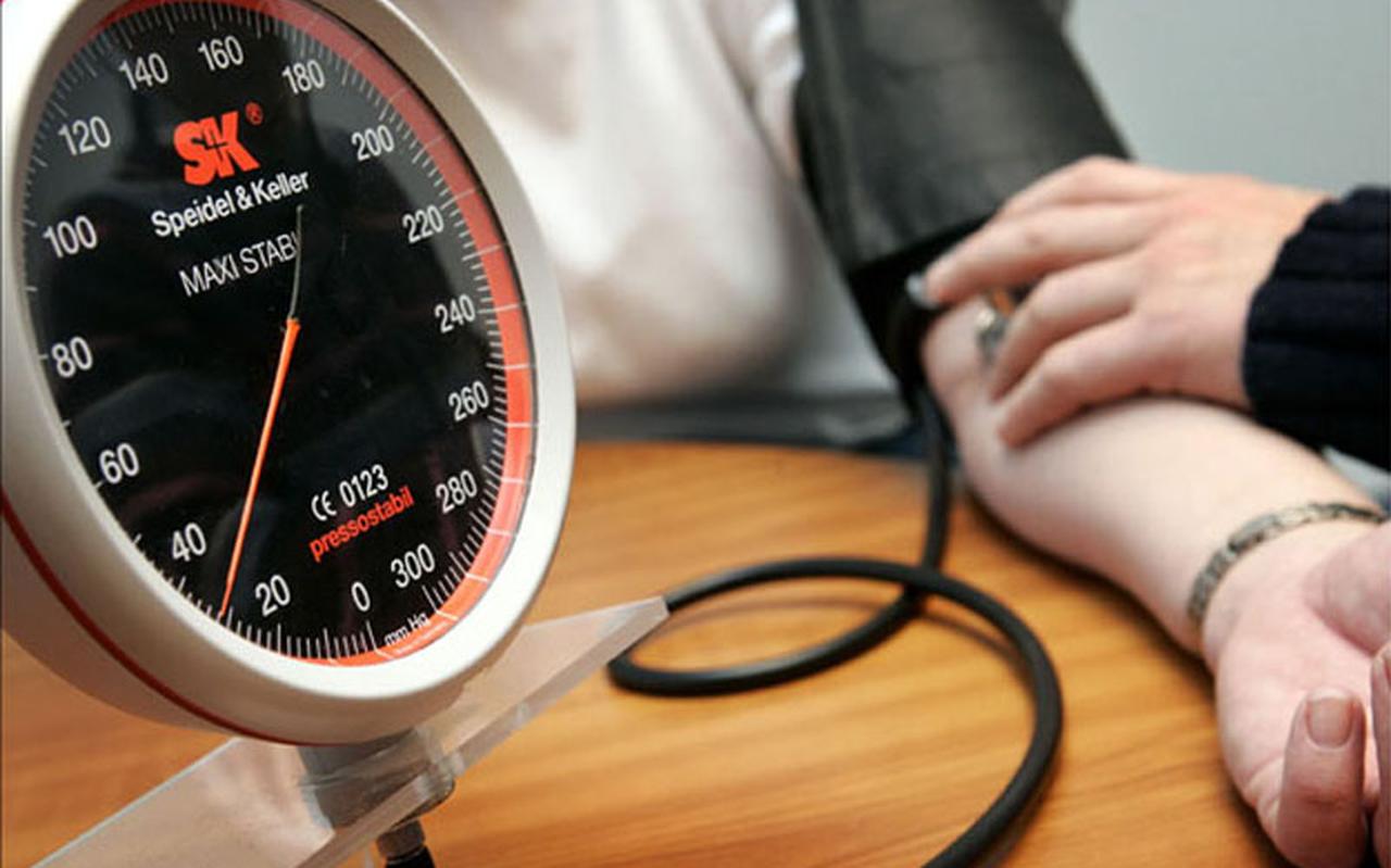 Een huisarts meet de bloeddruk van een patiënt. 