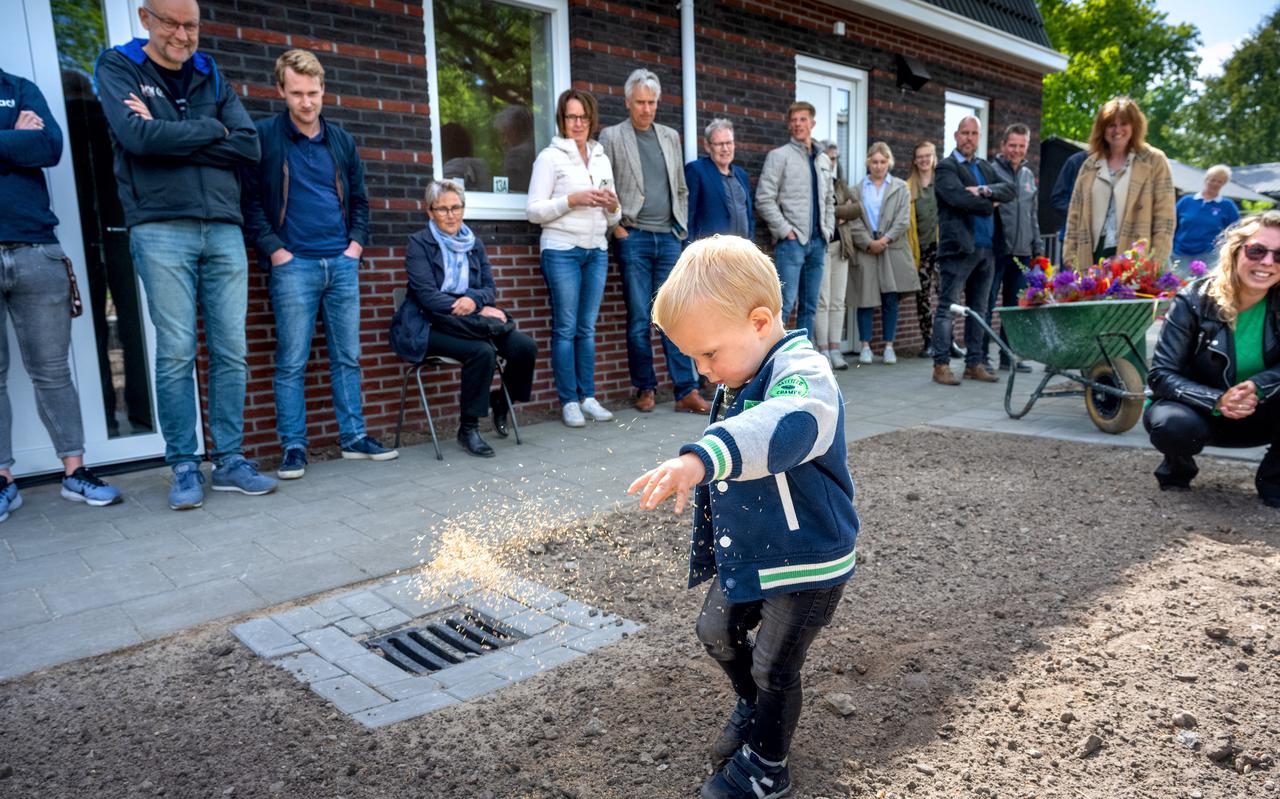 De 2-jarige Koen zaait graszaad bij zijn nieuwe huis, recht zijn moeder Sandra Barentsen.