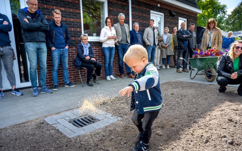 De 2-jarige Koen zaait graszaad bij zijn nieuwe huis, recht zijn moeder Sandra Barentsen. 
