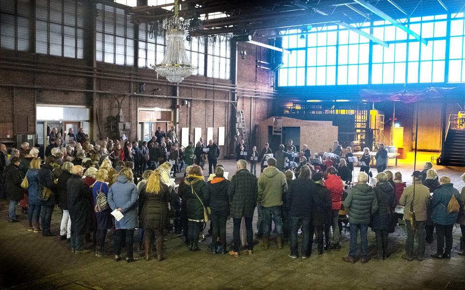 In de grote hal van de Sluisfabriek staat een grote groep deelnemers samen te zingen tijdens een eerdere kerstsamenzang.