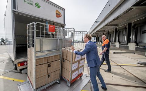 Wethouder Abel Reitsma laadt de eerste dozen in de vrachtwagen die voor de pilot zal worden gebruikt. Chauffeur Peter de Vries houdt een oogje in het zeil.