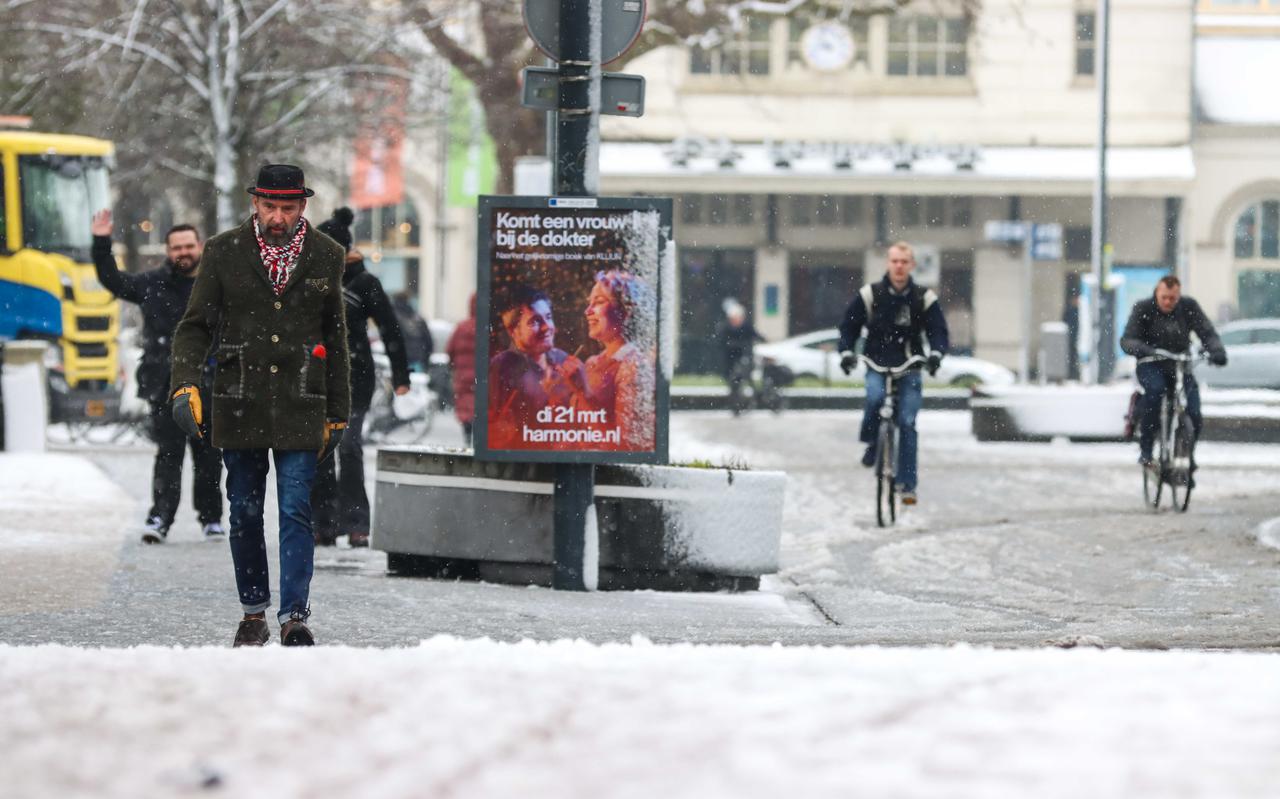 Mensen wandelen en fietsen door het besneeuwde centrum van Leeuwarden.