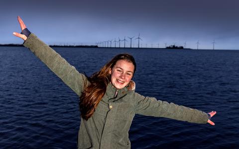 Marja Heldeweg op de pier in de baai van Lemmer met op de achtergrond windpark Westermeerwind in het IJsselmeer.
