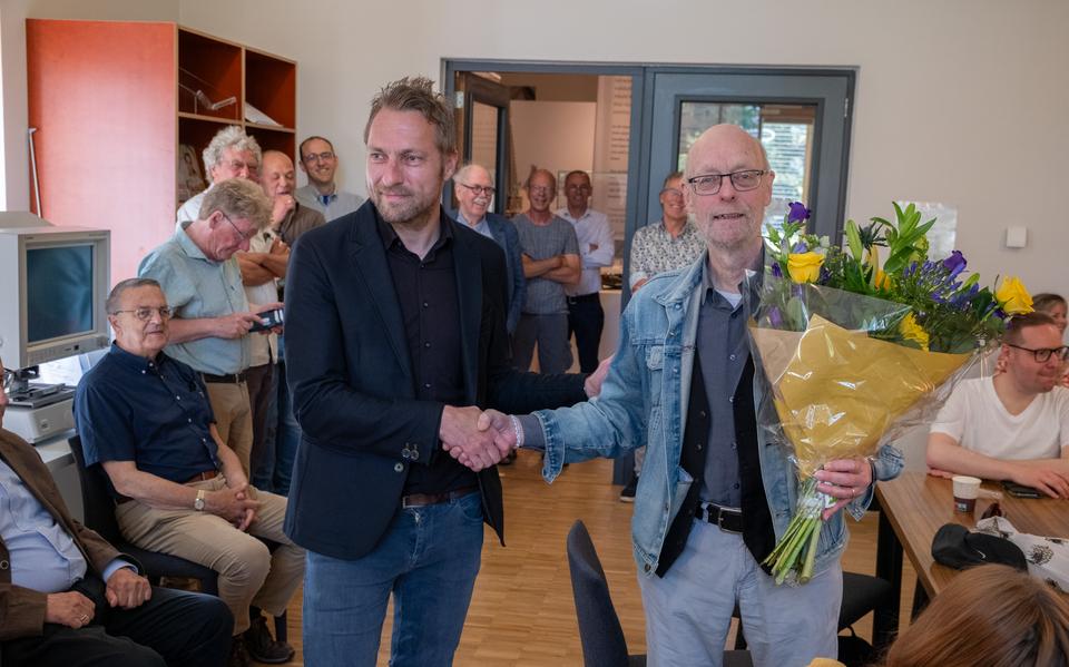 Leendert Plaisier heeft van wethouder Hein Kuiken het Leeuwarder Leeuwtje opgespeld gekregen en een bos bloemen gekregen. Achter hen zijn enkele andere eerder bekroonde Leeuwarders zichtbaar.