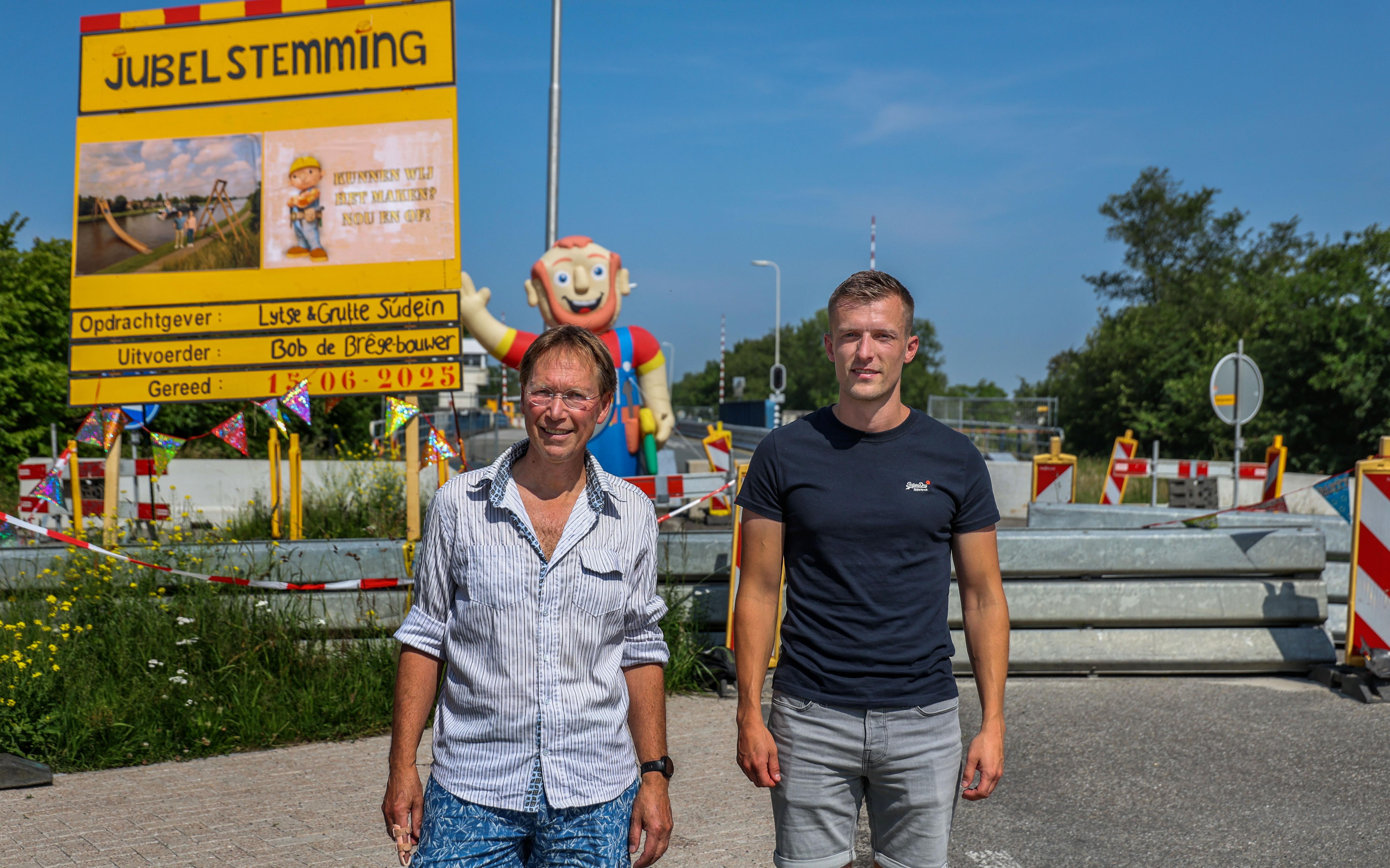 Steven Visser en Koos Oosterhaven voor het zelfgemaakte dorpsfeestbord met Bob de Bouwer in Uitwellingerga