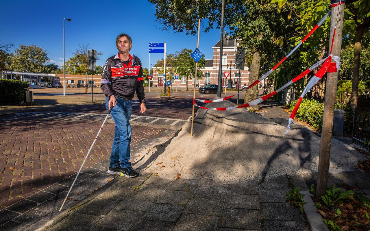Nico Smits zoekt voor het station in Sneek een looproute langs een obstakel op het voetpad.