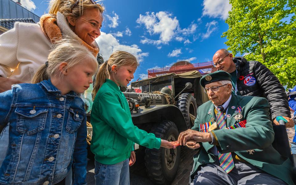 De Canadese veteraan Jim Parks deelt een pin uit met de Canadese vlag aan een jonge toeschouwer. 